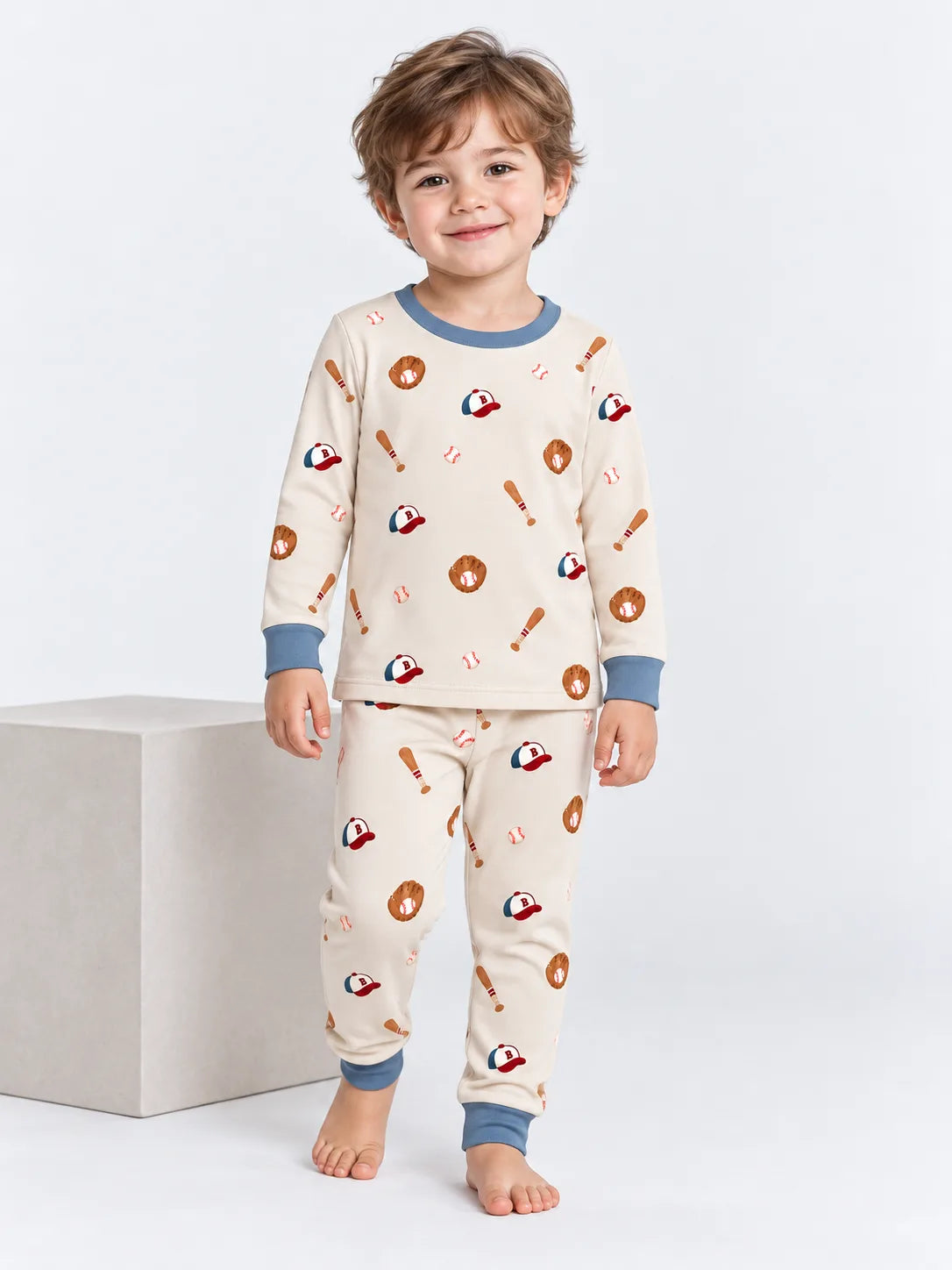 Toddler wearing Little Sluggers oatmeal grey bamboo baseball pajamas in a studio