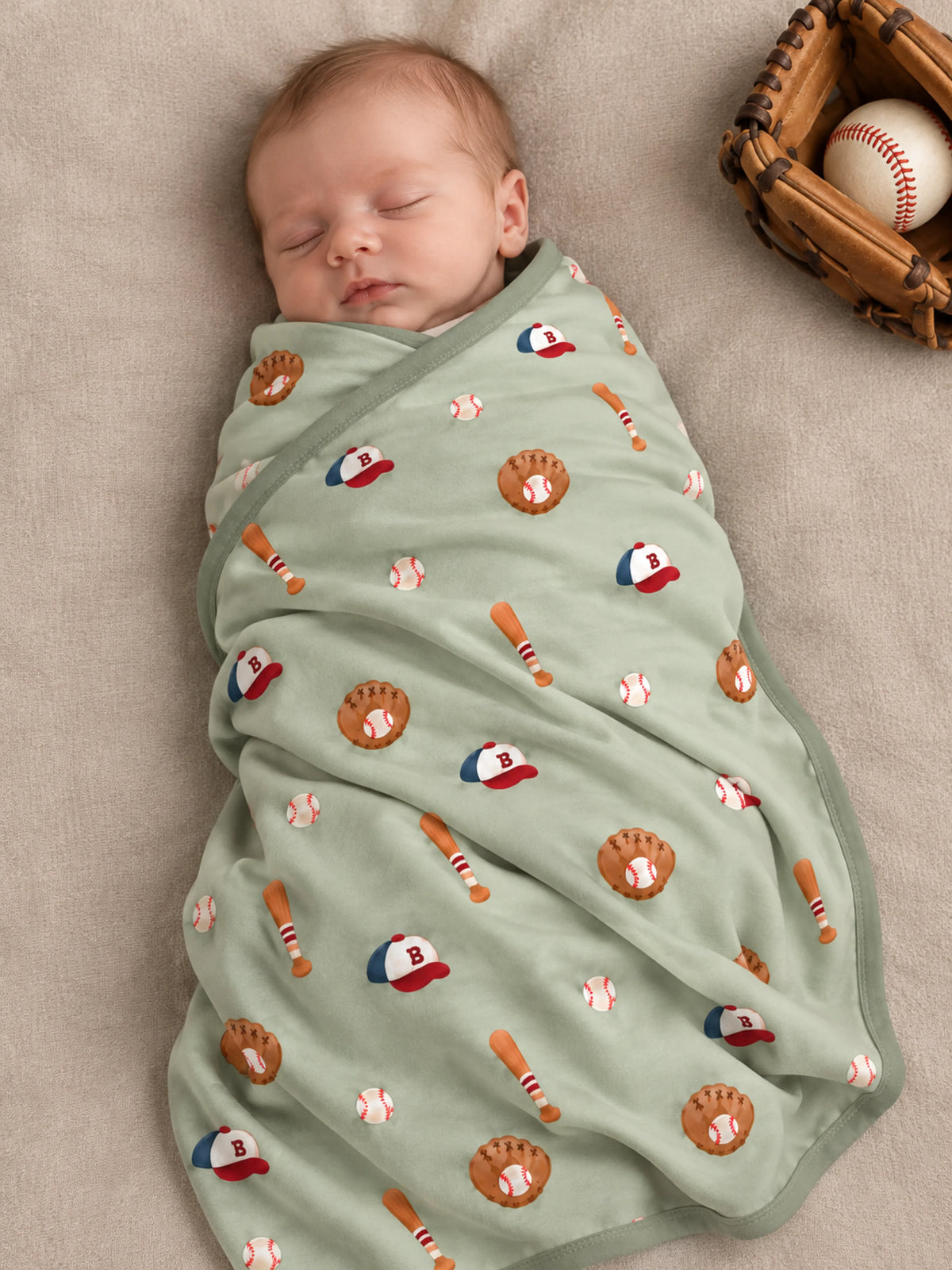 Baby lying on Little Sluggers sage green bamboo baseball blanket in a studio