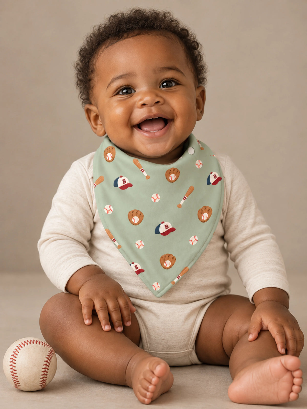 Baby wearing Little Sluggers sage green bamboo baseball bandana bib in a studio