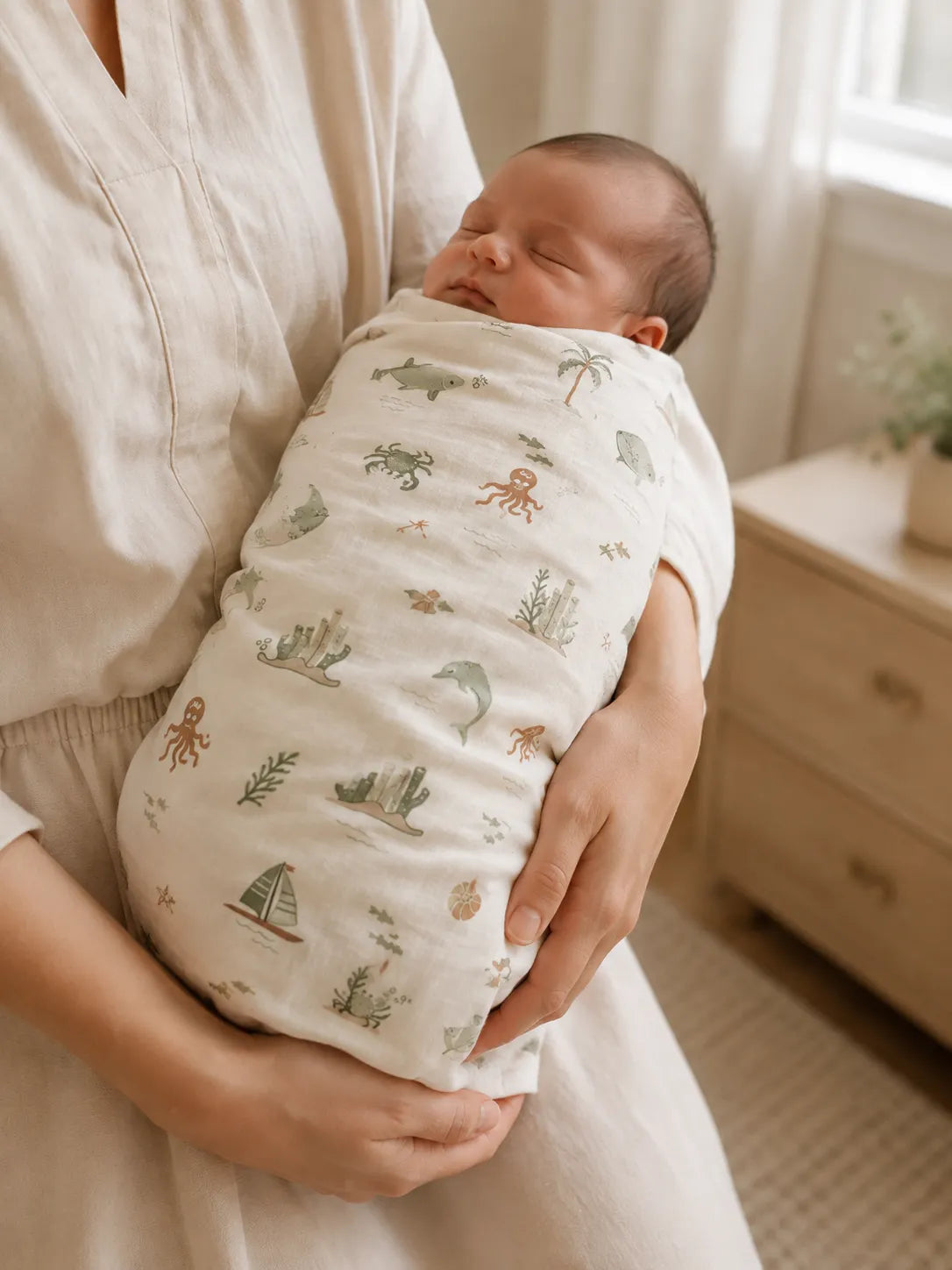 Baby cuddled in the Coastal Friends bamboo swaddle blanket at home