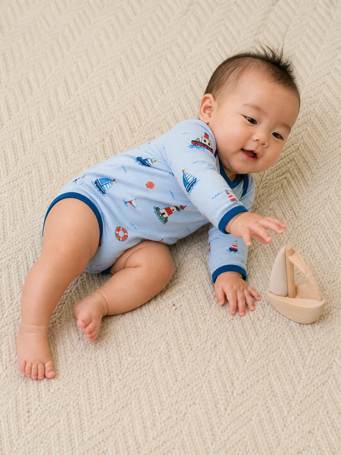 Baby playing comfortably in the Sail Away bamboo bodysuit
