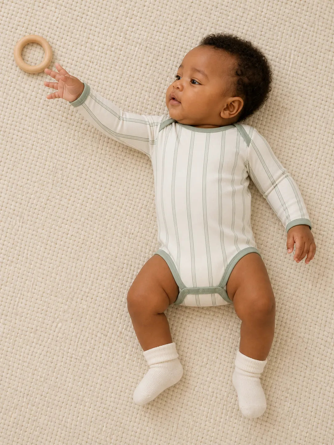 Baby playing comfortably in the Sage Stripe bamboo bodysuit