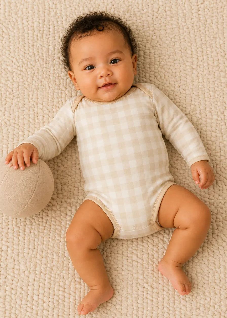 Baby playing comfortably in the Oat Gingham bamboo bodysuit