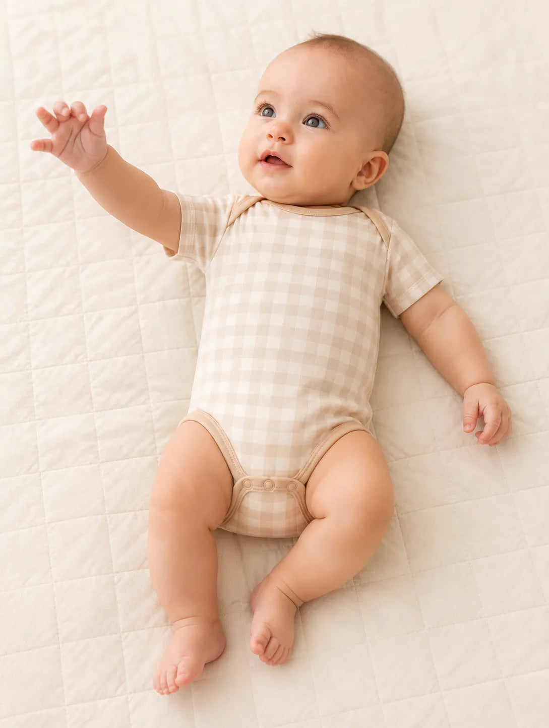 Baby playing comfortably in the Oat Gingham bamboo bodysuit