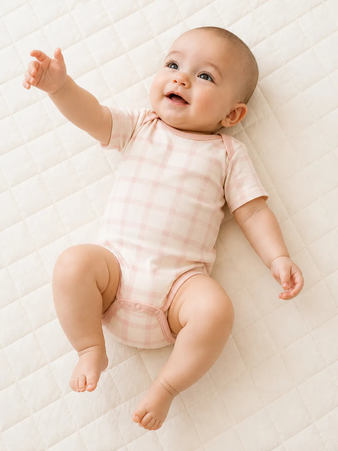 Baby playing comfortably in the Blush Plaid bamboo bodysuit