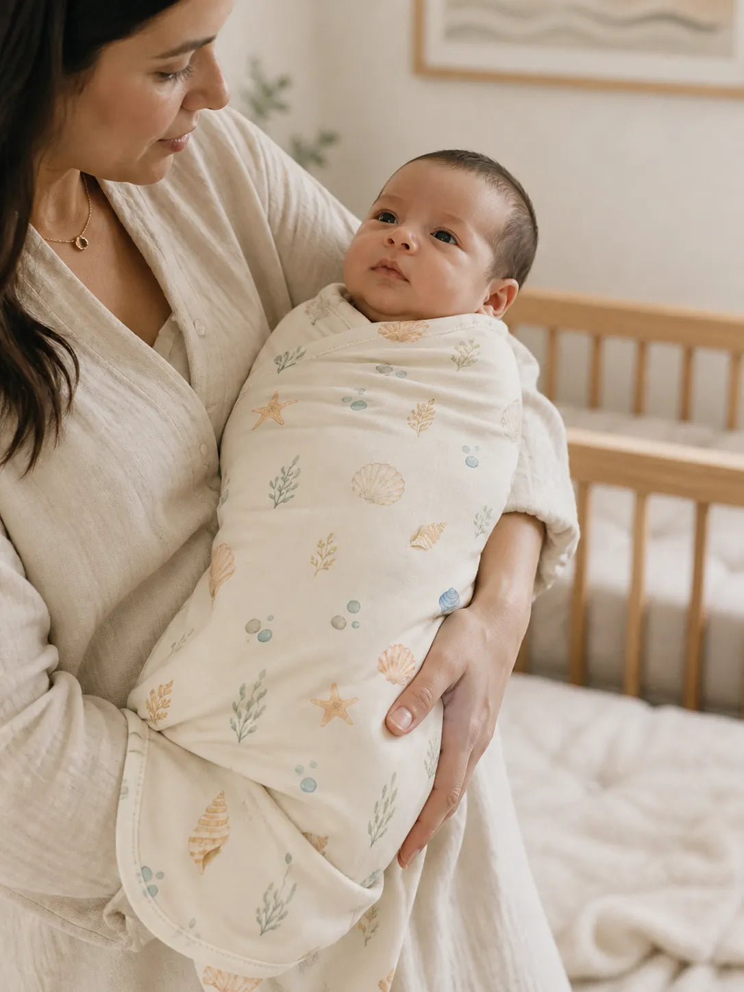 Baby cuddled in the Seaside Treasures bamboo swaddle blanket at home