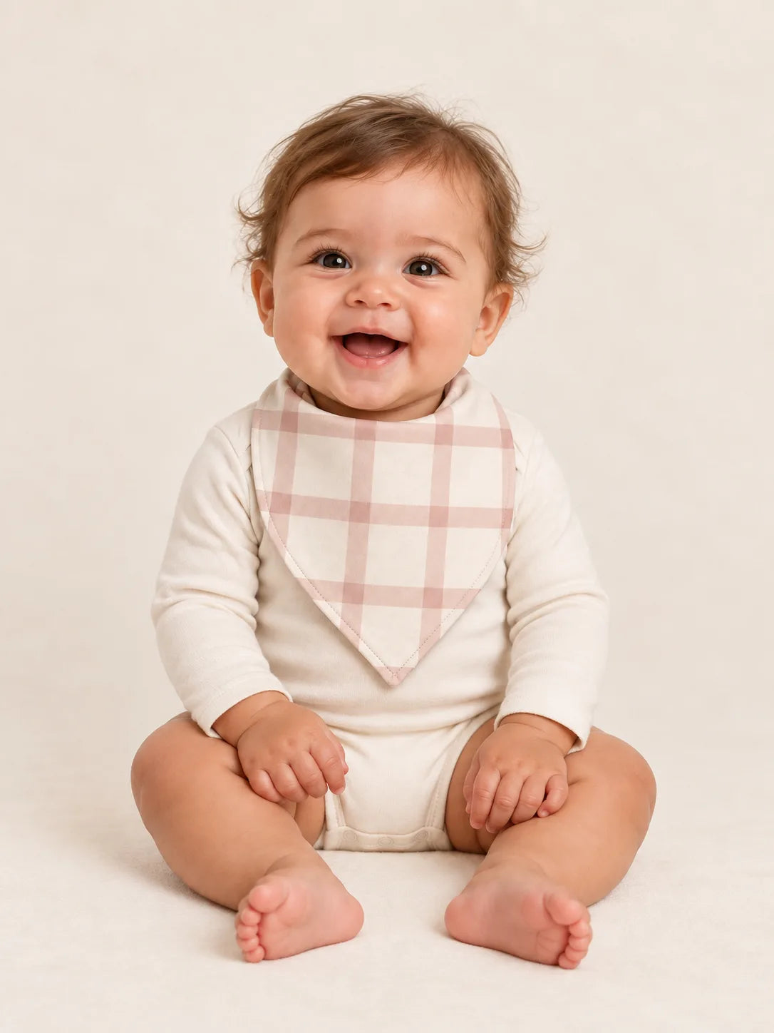 Baby wearing the MossiBaby Blush Plaid bandana bib with an ivory long-sleeve bodysuit