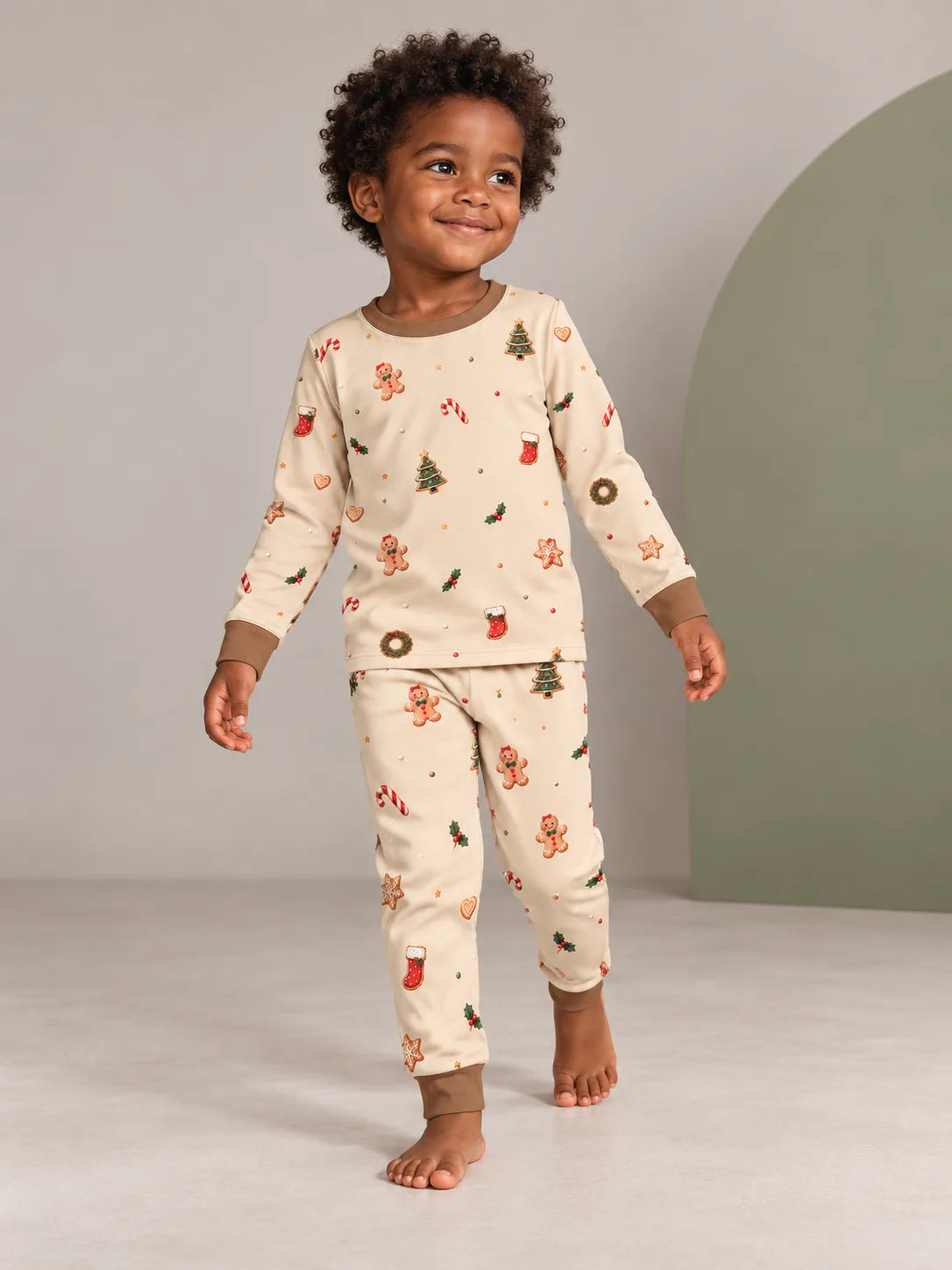Toddler stepping forward in the MossiBaby Christmas Joy pajama set against a neutral studio backdrop.