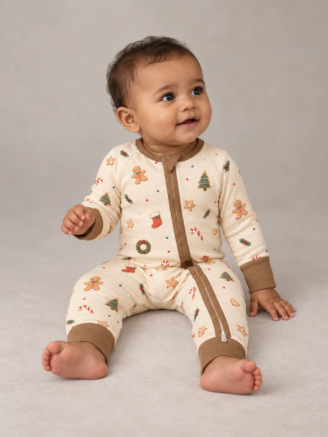 Baby sitting in the MossiBaby Christmas Joy zipper romper with the front zipper and ankle cuffs visible.