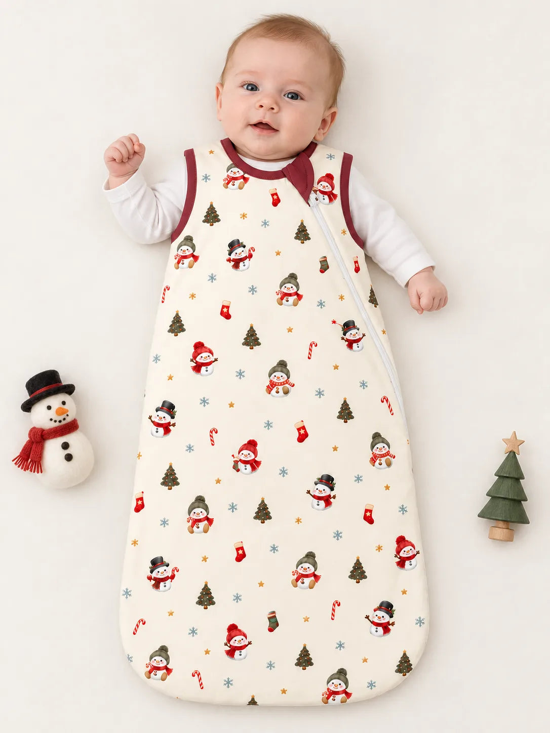 Baby lying on a studio mat wearing Mossibaby Christmas Snowman ivory cream bamboo sleep bag with cranberry red trim