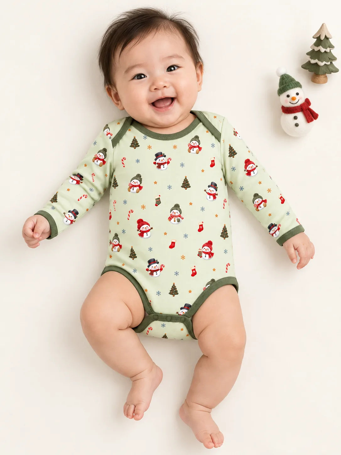 Baby lying on a studio mat wearing Mossibaby Christmas Snowman pale green bamboo long sleeve bodysuit with olive green trim