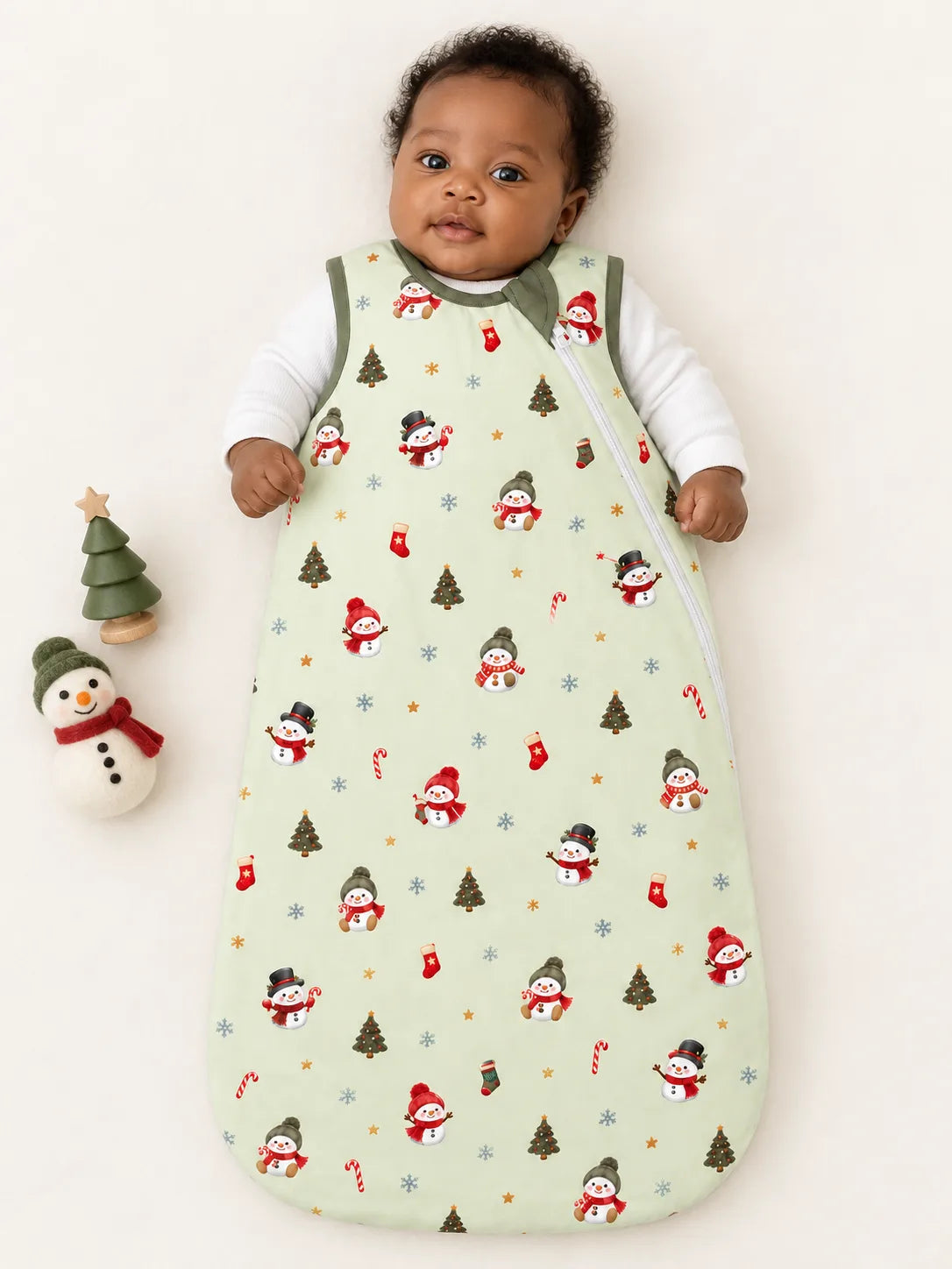 Baby lying on a studio mat wearing Mossibaby Christmas Snowman pale green bamboo sleep bag with olive green trim