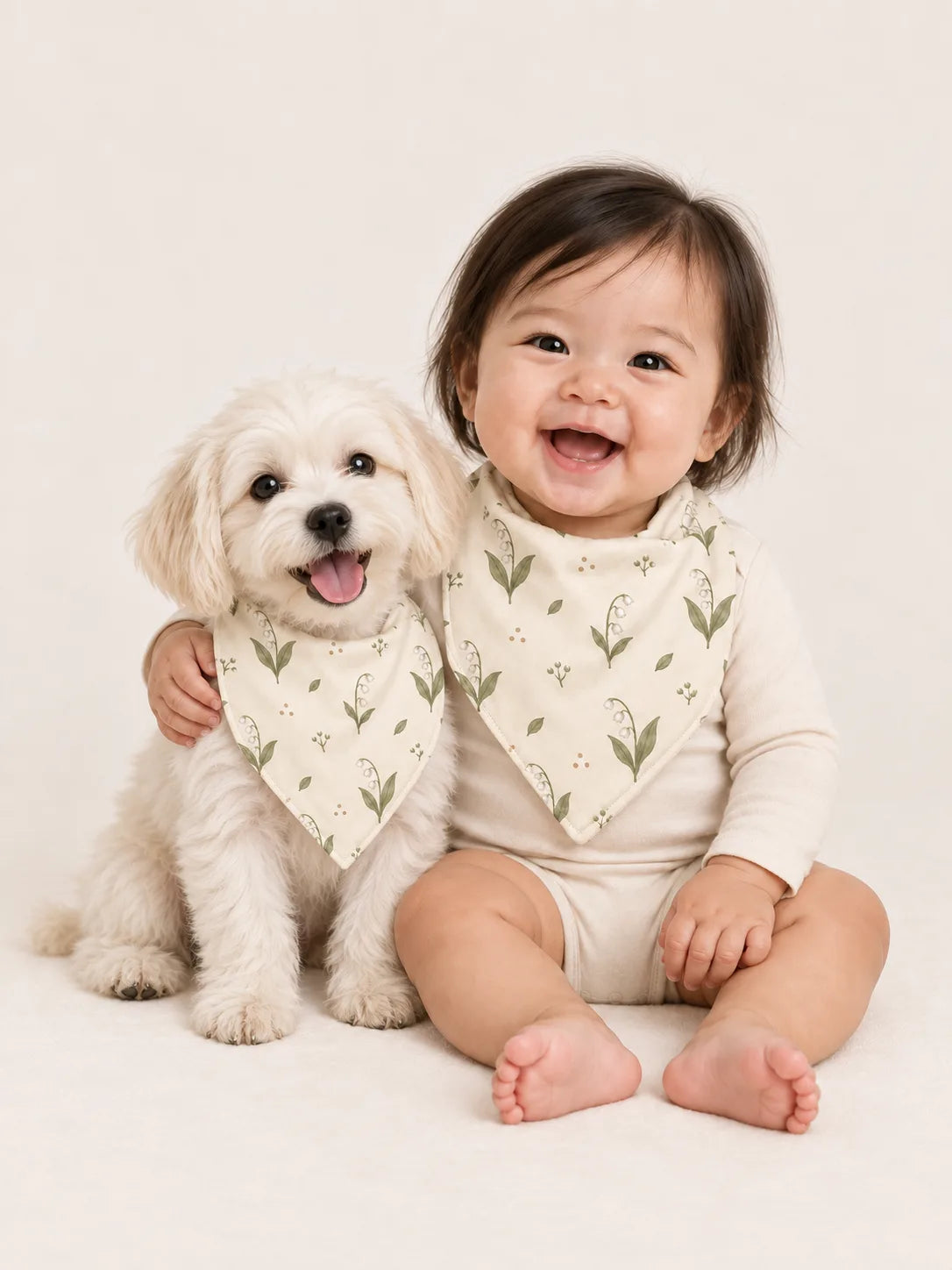 Baby and Maltese puppy wearing matching MossiBaby Little Botanicals bandana bibs
