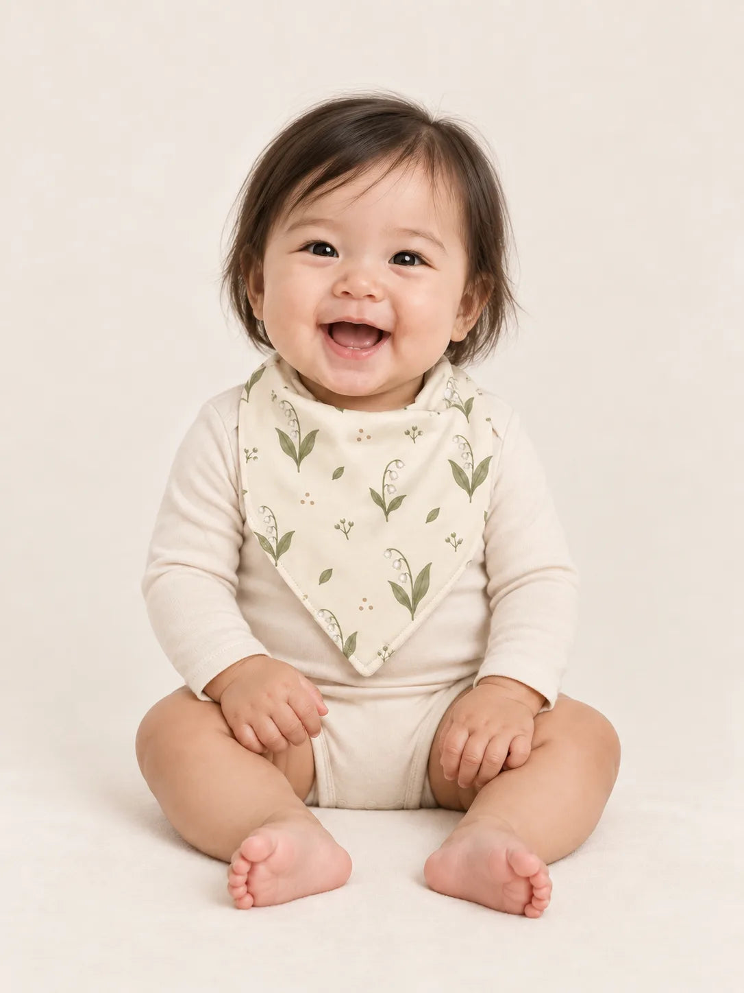 Baby wearing the MossiBaby Little Botanicals bandana bib with an ivory long-sleeve bodysuit