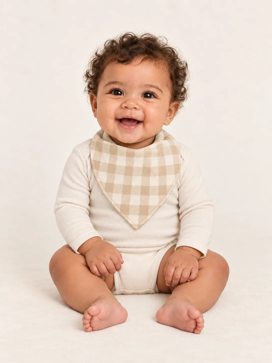 Baby wearing the MossiBaby Oat Gingham bandana bib with an ivory long-sleeve bodysuit