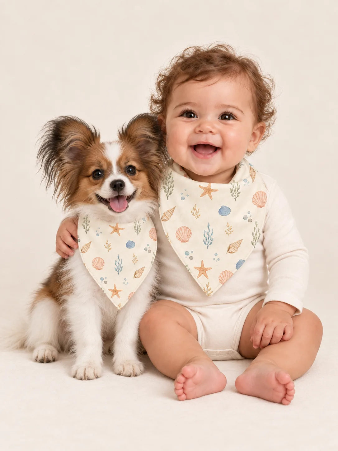 Baby and Papillon puppy wearing matching MossiBaby Seaside Treasures bandana bibs