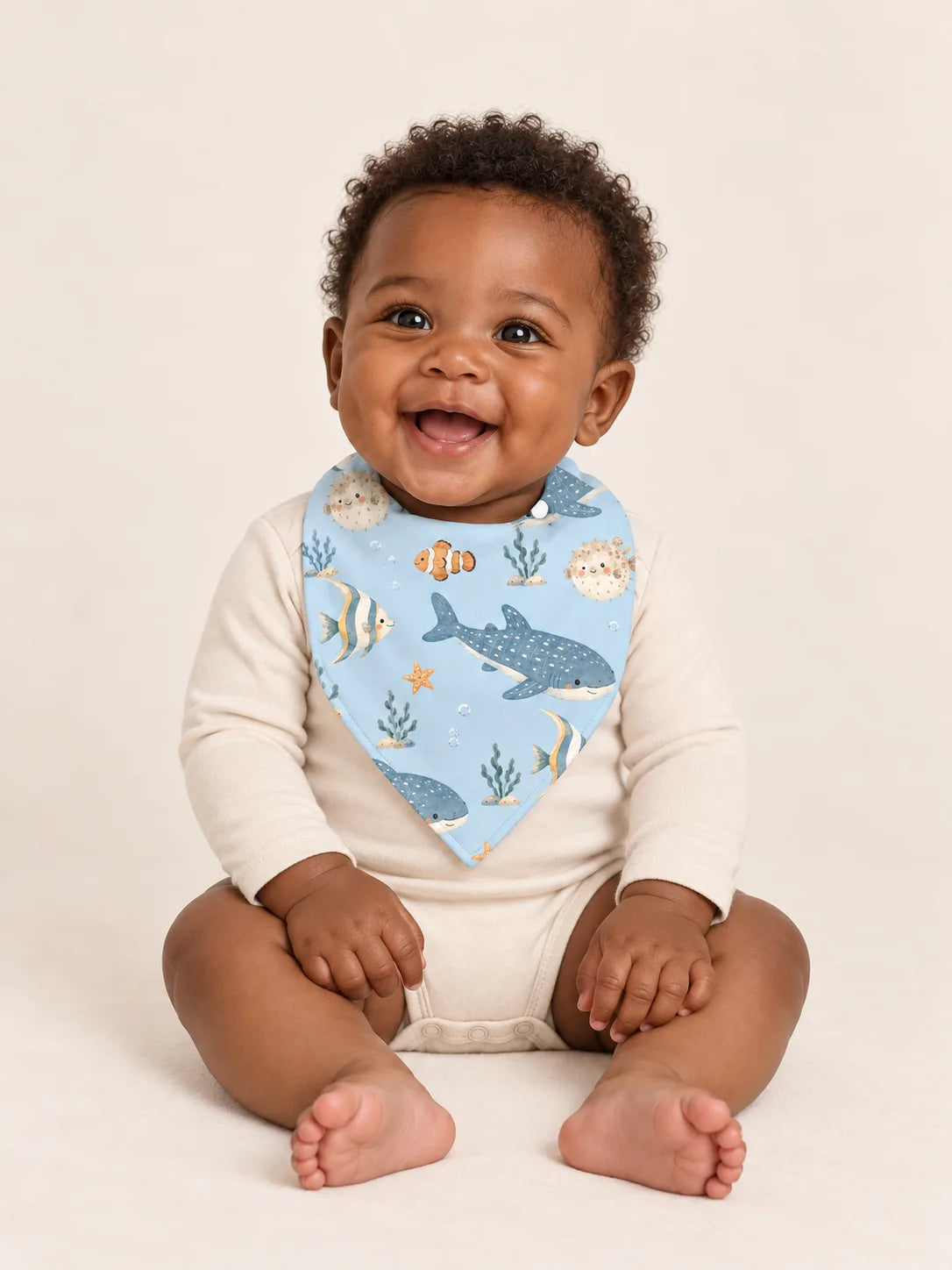 Baby wearing the MossiBaby Shark Cove bandana bib with an ivory long-sleeve bodysuit