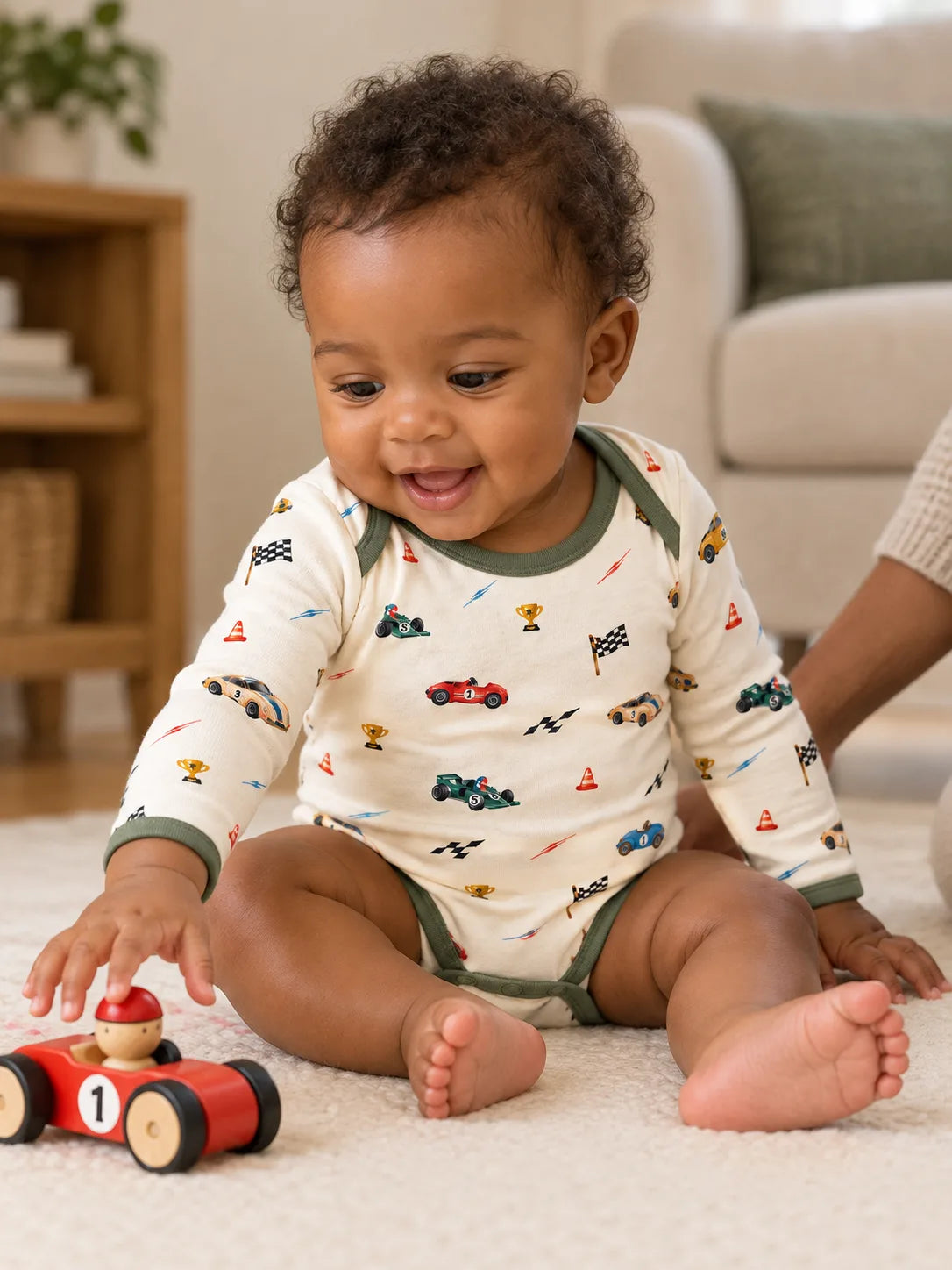 Baby wearing the Vintage Racers bamboo long sleeve bodysuit while reaching for a toy racing car at home.