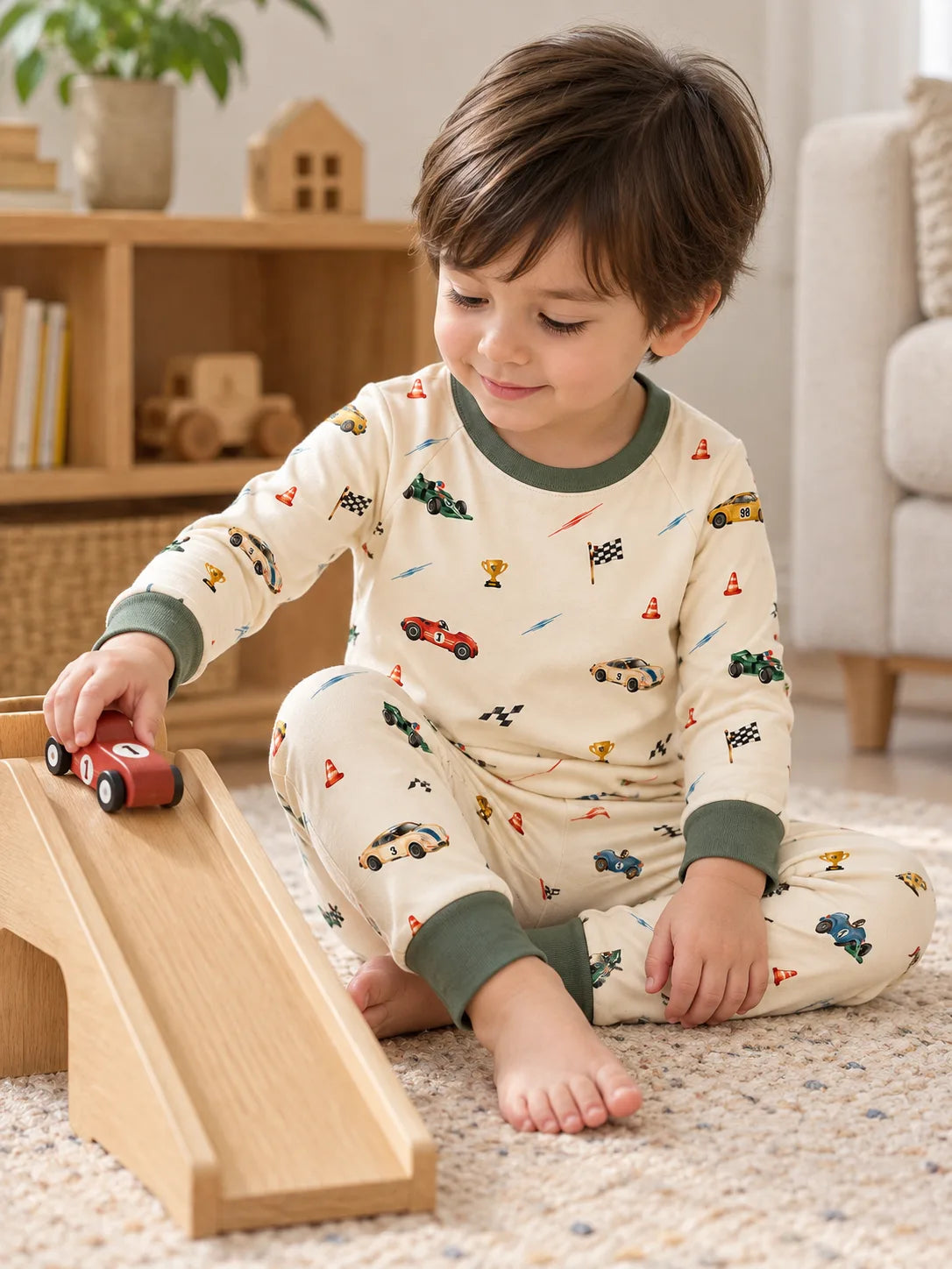 Child wearing the Vintage Racers bamboo pajama set while playing with a toy car and wooden ramp at home.