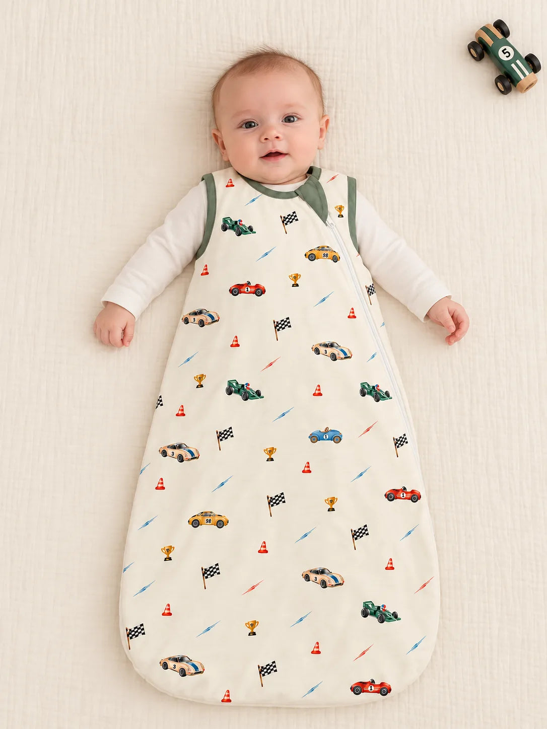 Baby lying in the Vintage Racers bamboo sleep bag over an ivory bodysuit in a studio.