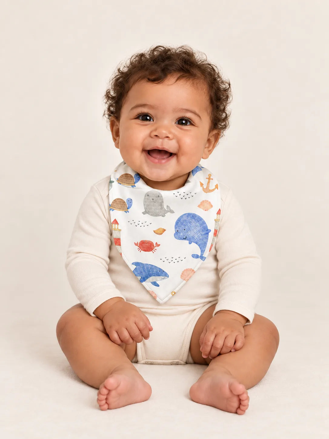 Baby wearing the MossiBaby Whale Harbor bandana bib with an ivory long-sleeve bodysuit