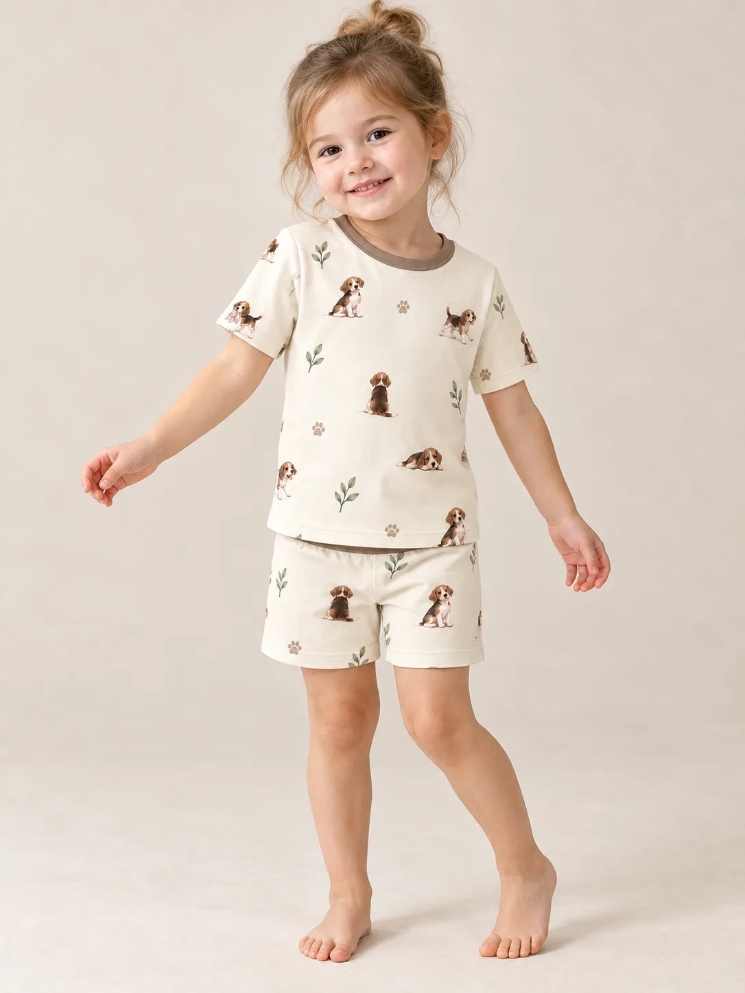 Child wearing the MossiBaby beagle buddies short sleeve pajama set against a pale studio backdrop