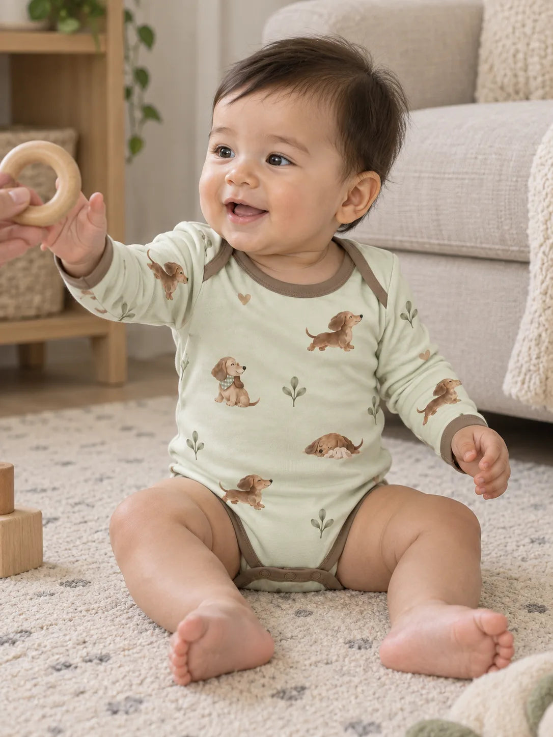 Baby wearing the MossiBaby dachshund meadow long sleeve bodysuit in an indoor lifestyle scene