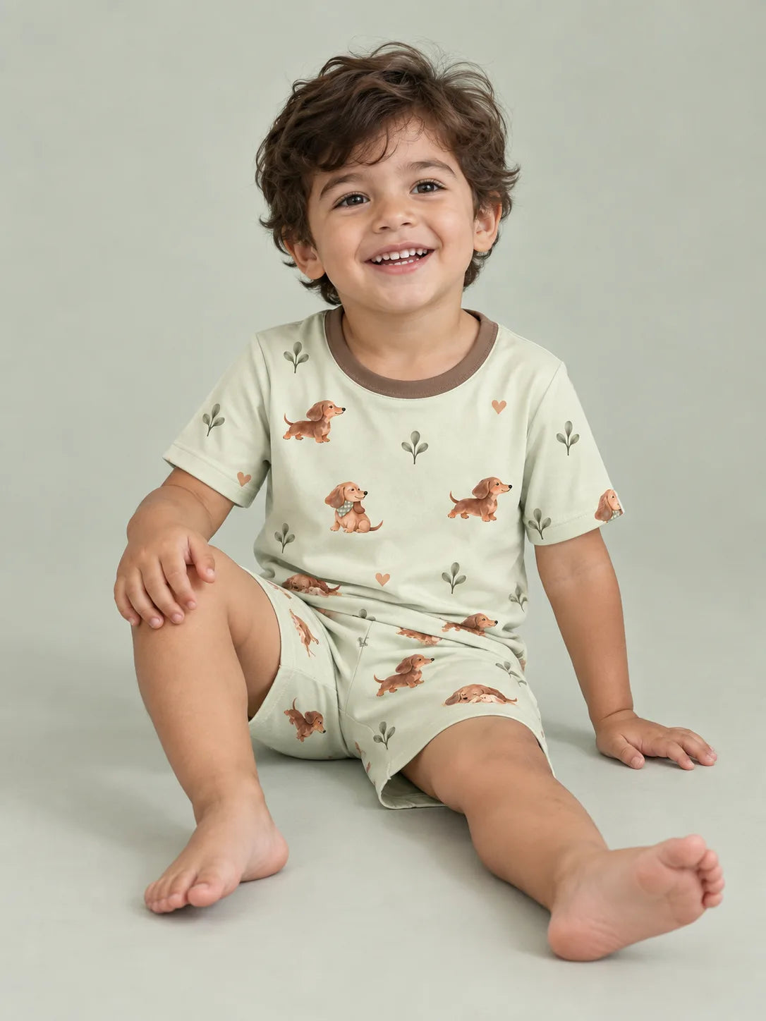 Child wearing the MossiBaby dachshund meadow short sleeve pajama set against a pale studio backdrop