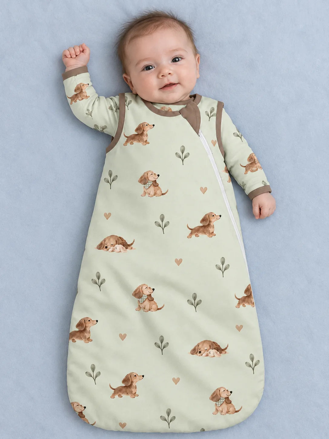 Baby wearing the MossiBaby dachshund meadow sleep bag against a pale studio backdrop