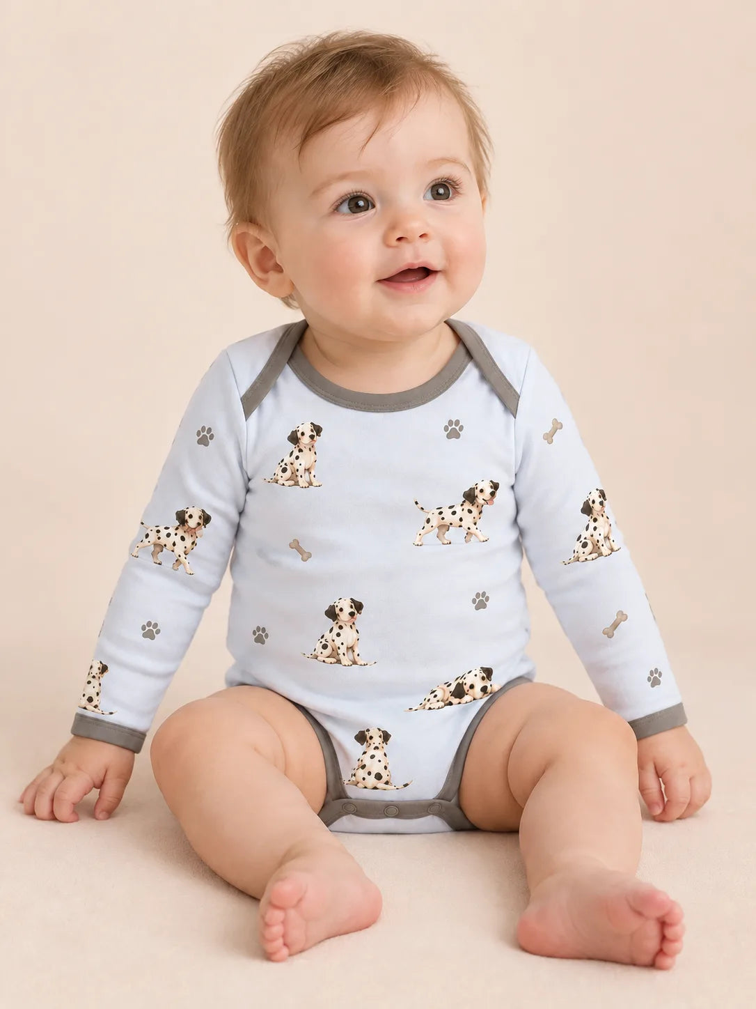 Baby wearing the MossiBaby dalmatian days long sleeve bodysuit against a pale studio backdrop