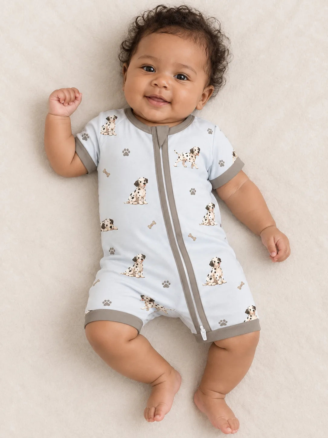 Baby wearing the MossiBaby dalmatian days shorty romper against a pale studio backdrop