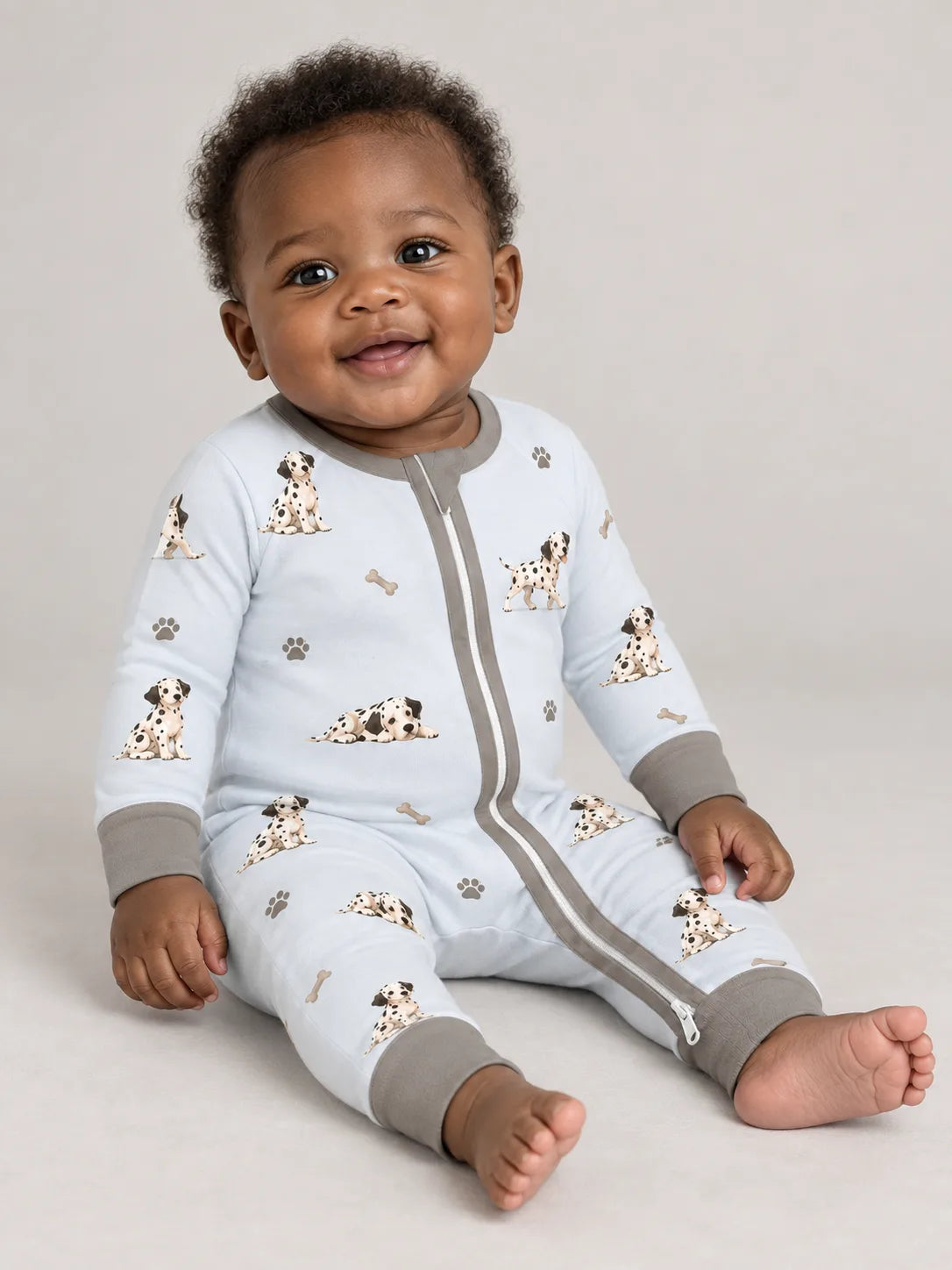 Baby wearing the MossiBaby dalmatian days zipper romper against a pale studio backdrop