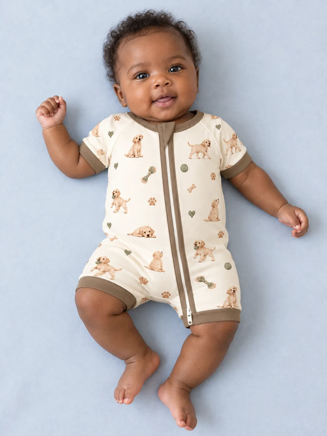 Baby wearing the MossiBaby little labradors shorty romper against a pale studio backdrop