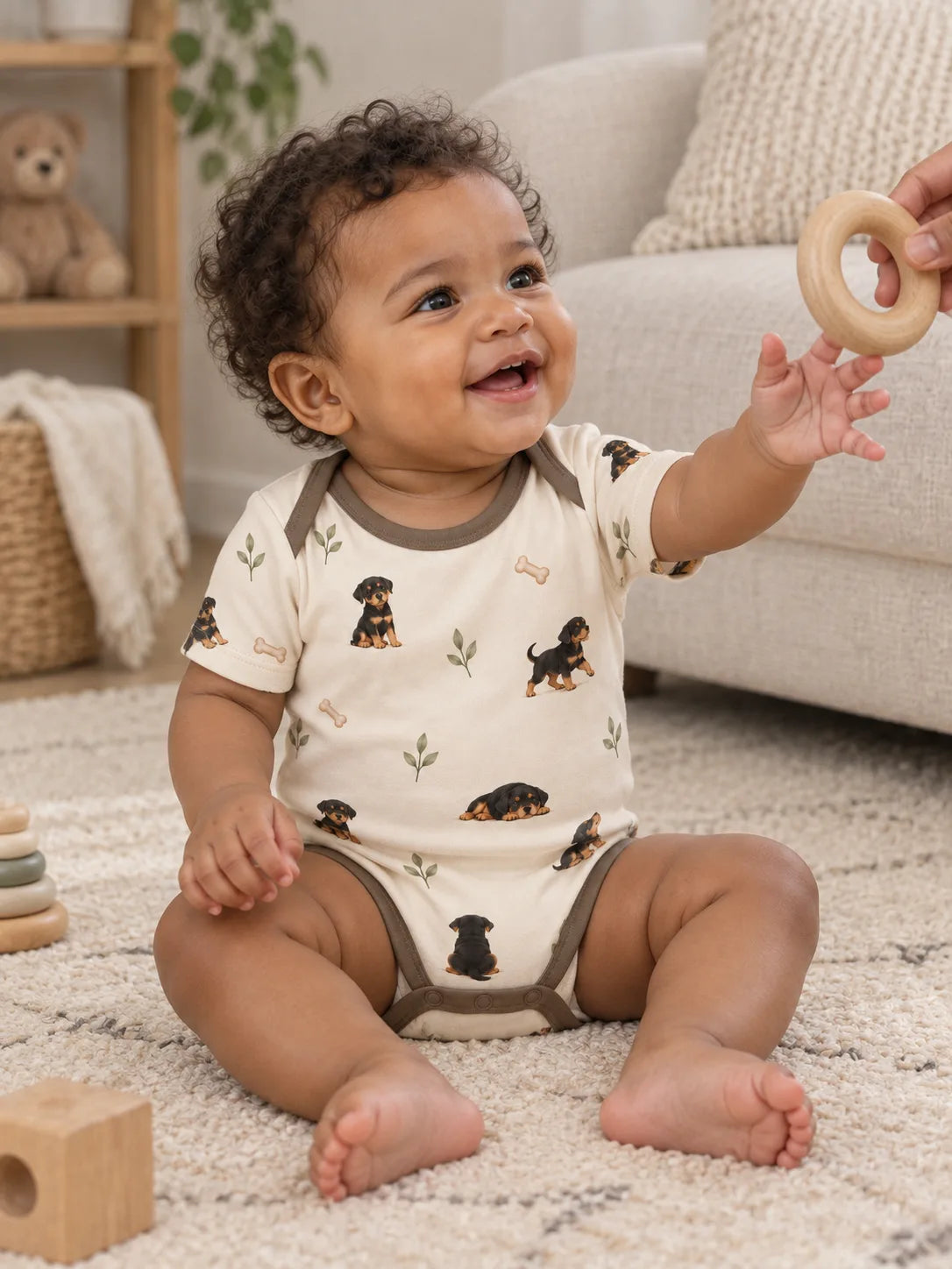 Baby wearing the MossiBaby rottie cuddles short sleeve bodysuit in an indoor lifestyle scene
