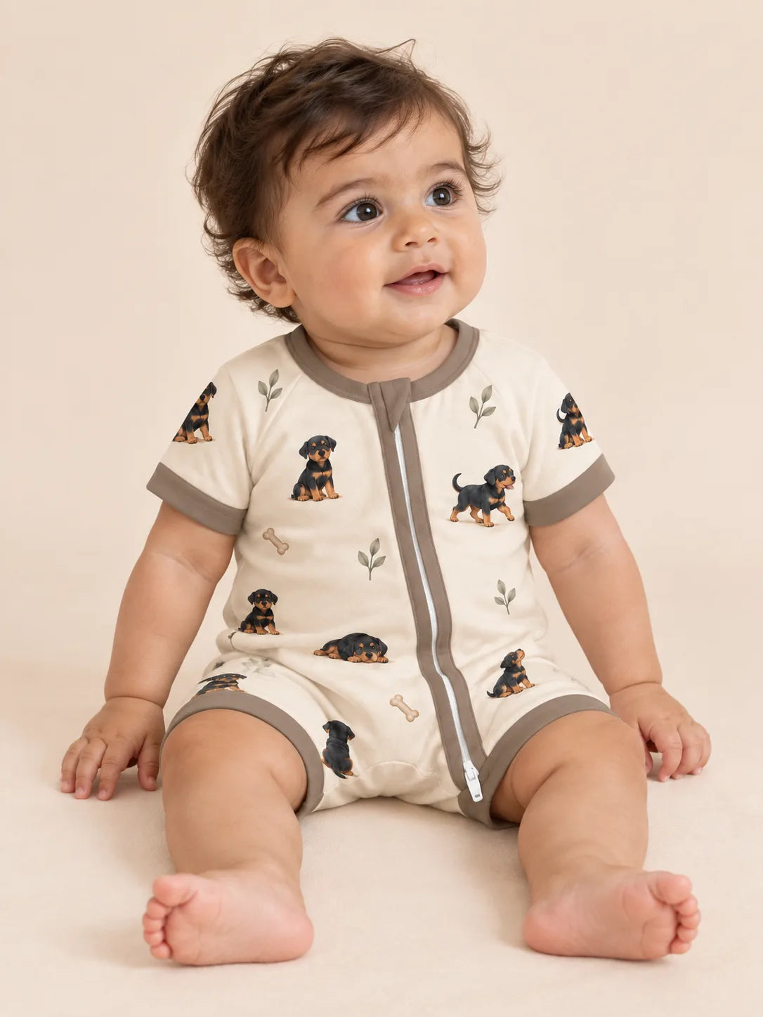 Baby wearing the MossiBaby rottie cuddles shorty romper against a pale studio backdrop