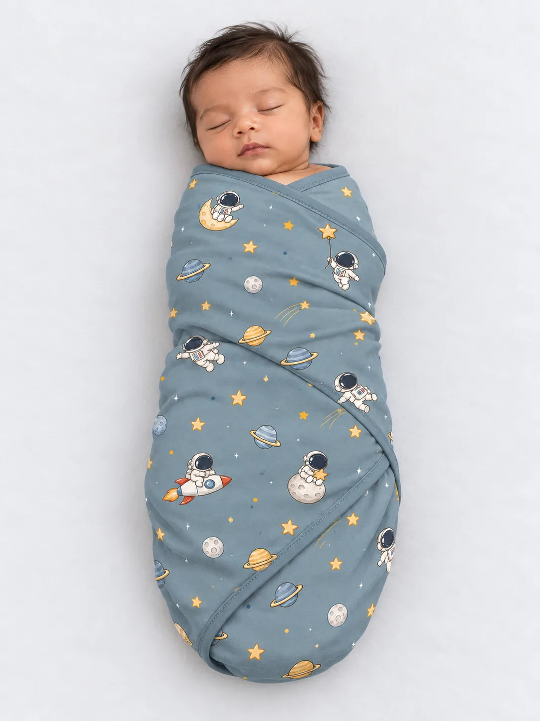 Baby lying on Mossibaby Space Adventures denim blue bamboo baby blanket in a studio