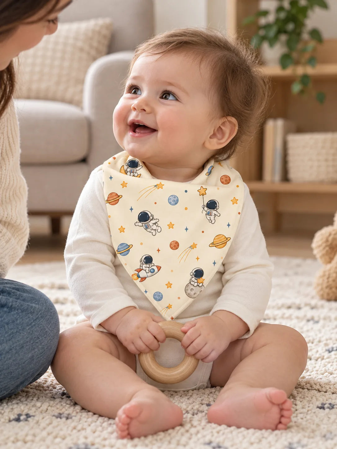 Baby wearing an ivory Space Adventures bamboo bandana bib during playtime at home